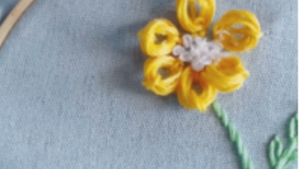 flor bordada en relieve de petalos amarillos y centro blanco, tallo verde